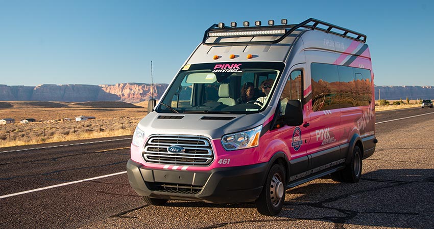 Pink Jeep Tour's Adventure Tour Trekker on road to Antelope Canyon with desert view in background.