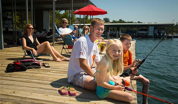 A family sitting on a dockside pier and fishing in Table Rock Lake, Branson, MO.