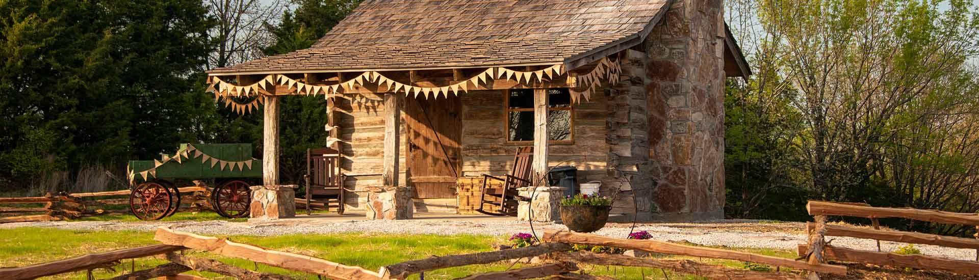 Header image of a historic log cabin atop Baird Mountain glowing in the afternoon sun with a rail fence in the foreground.