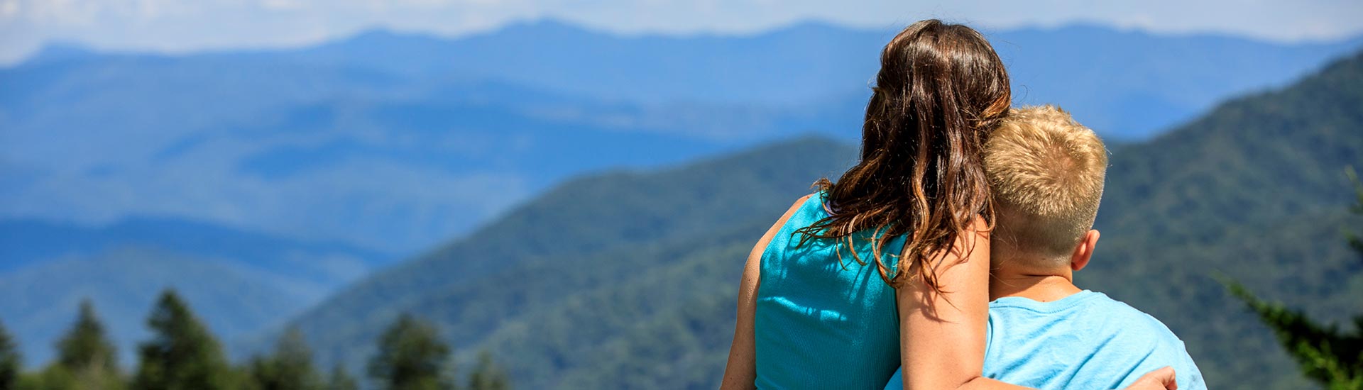 Mother and son embraced, looking out towards the Smoky Mountains from Newfound Gap