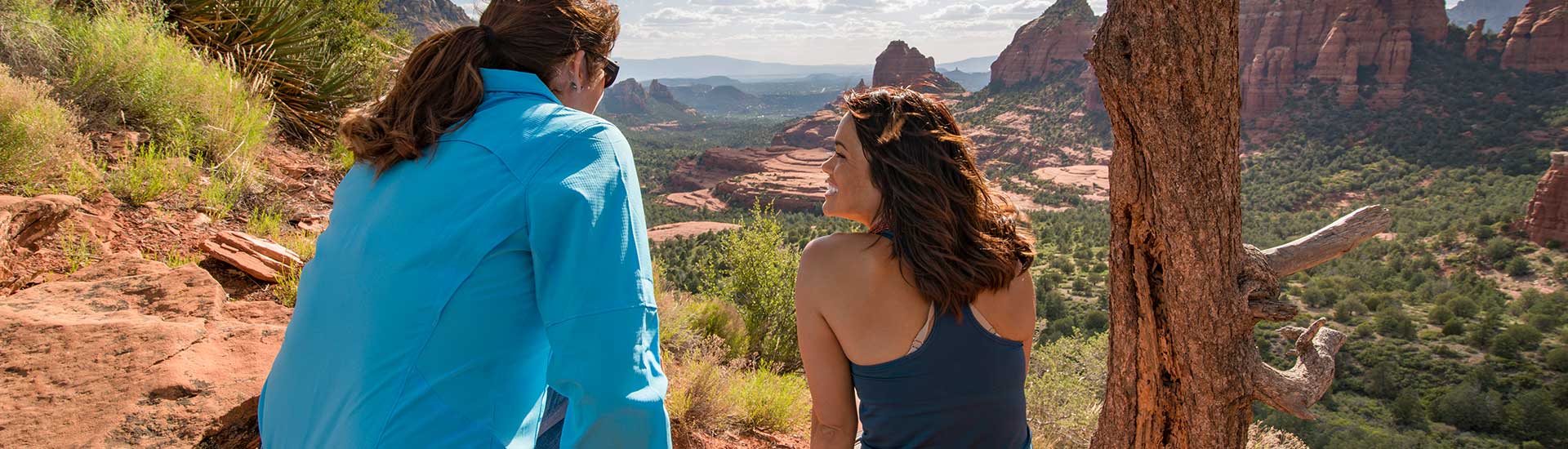 Couple seated at the edge of the Mogollon Rim, looking down Bear Wallow Canyon towards Sedona, AZ.