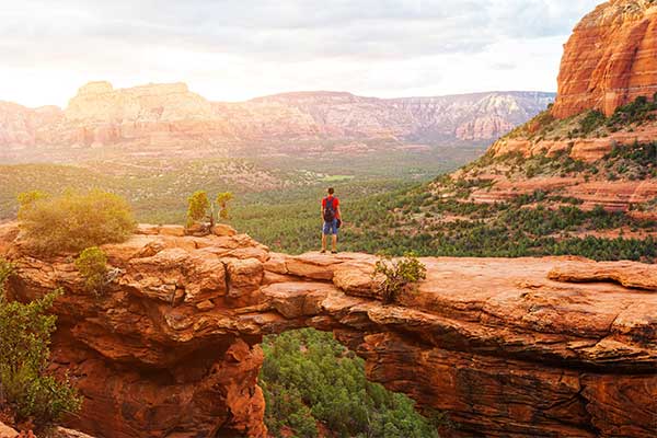 Hiker standing on Devil's Bridge at sunrise, Sedona, AZ