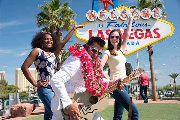 Two women posing with Evis in front of Welcome to Las Vegas sign